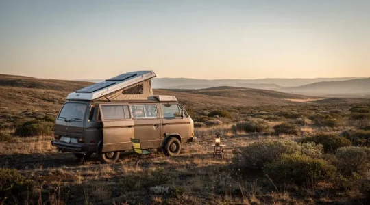 A self-sufficient camper van parked alone in a vast, remote wilderness landscape at dusk, fully equipped for an extended off-grid stay.